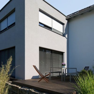 Graues Haus mit dunklen Rollladen